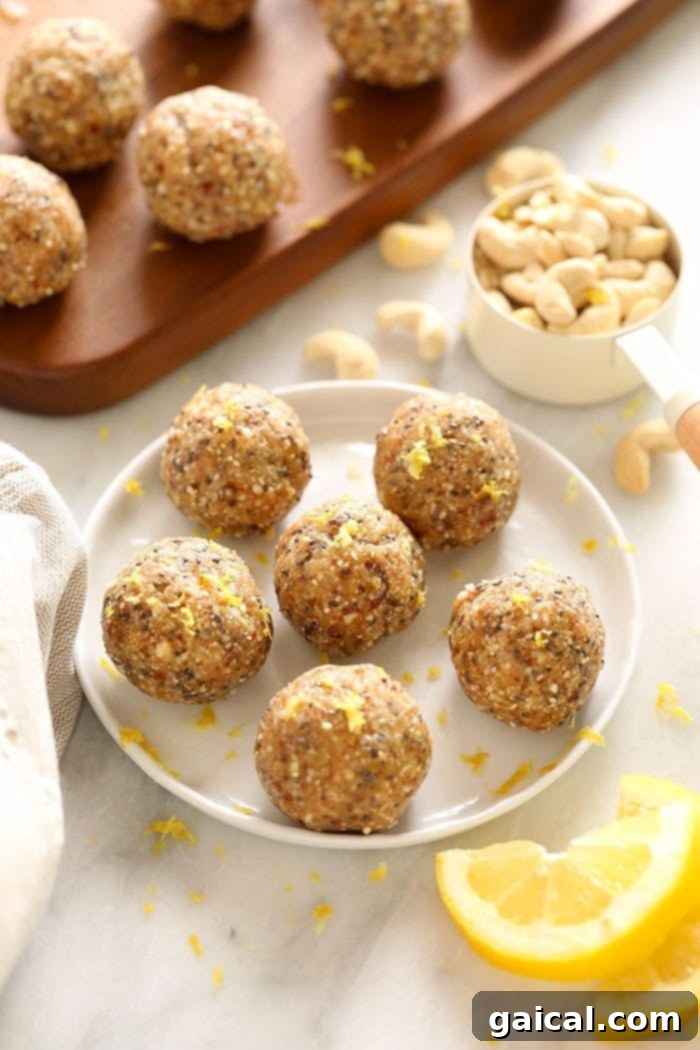 Lemon Energy Balls Ready to Freeze Freshly rolled lemon cake energy balls, sprinkled with lemon zest, are cooling on a plate, showcasing their vibrant color and inviting texture.