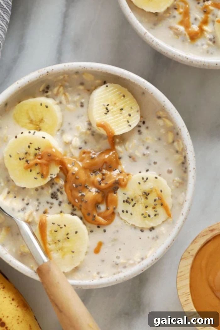 With mashed bananas and Greek yogurt, these Creamy Banana Overnight Oats are the perfect start to the day! Make a batch of these overnight oats today, and enjoy for breakfast all week long. This healthy overnight oats recipe is calling your name! A close-up of creamy banana overnight oats in a bowl, generously topped with fresh banana slices and a sprinkle of chia seeds, ready to be eaten.
