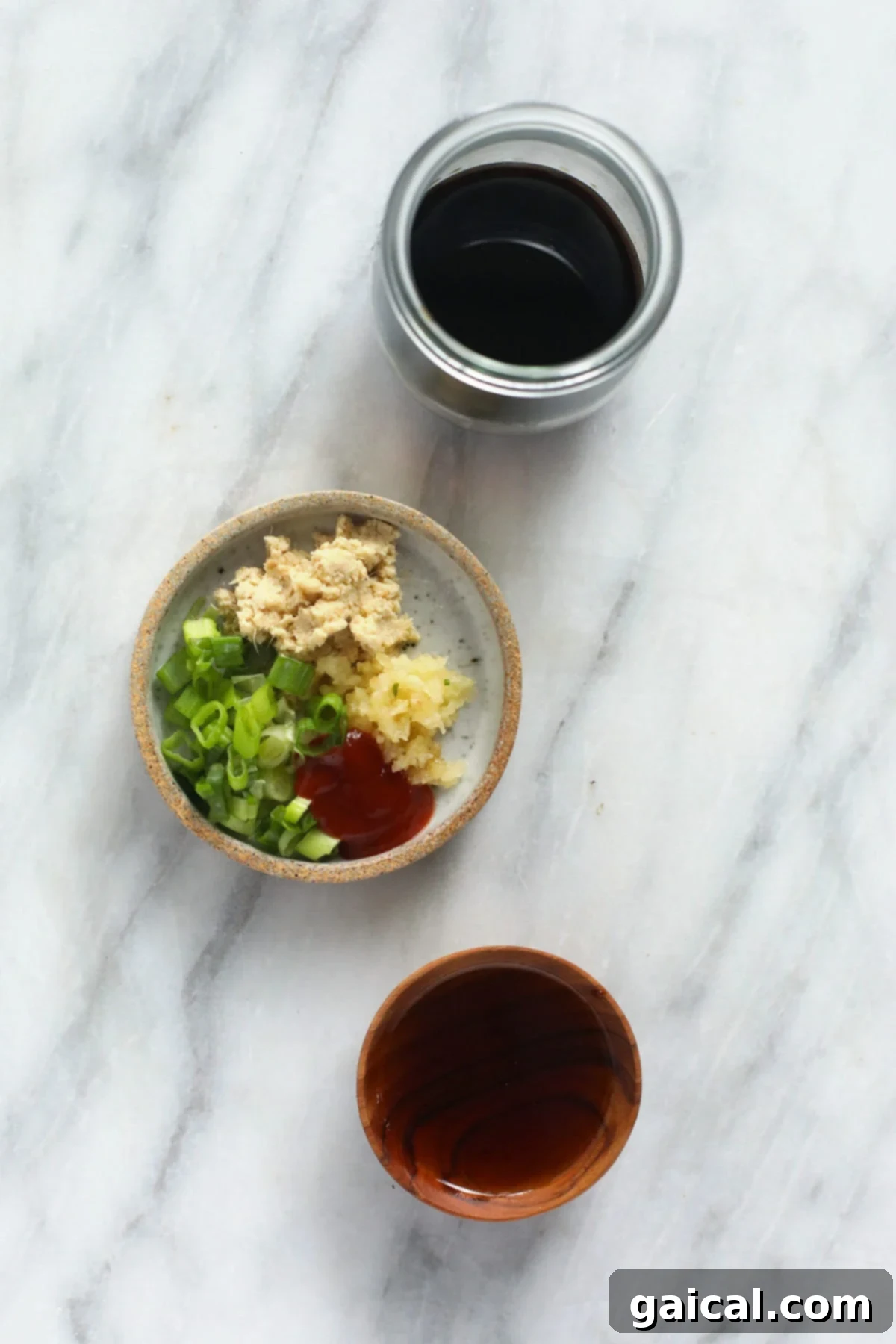 A collection of fresh ingredients used to make homemade teriyaki sauce, including soy sauce, maple syrup, ginger, and garlic.