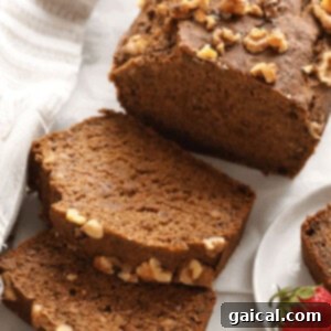 A perfectly baked and sliced vegan banana bread loaf on a wooden cutting board.