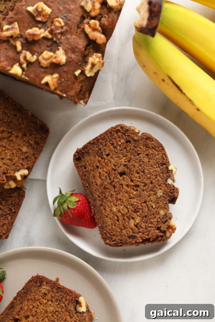A slice of fluffy vegan banana bread on a white plate, ready to be enjoyed with a cup of coffee.