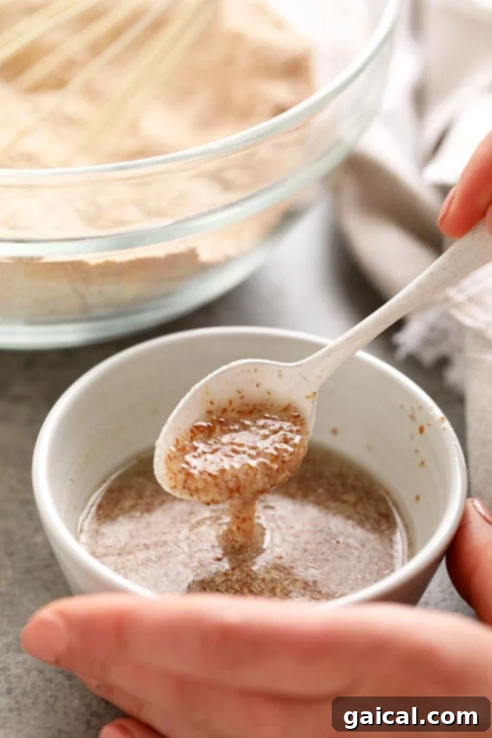 A close-up of a fully gelled flax egg in a bowl with a spoon, demonstrating its thick, viscous texture and readiness for use in baking.
