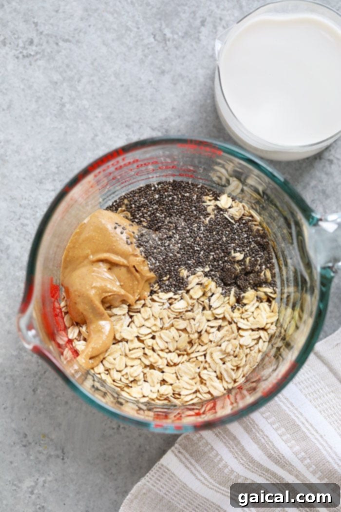 Separated ingredients for Peanut Butter Overnight Oats: rolled oats, a spoon of peanut butter, a spoon of chia seeds, and a glass of almond milk.