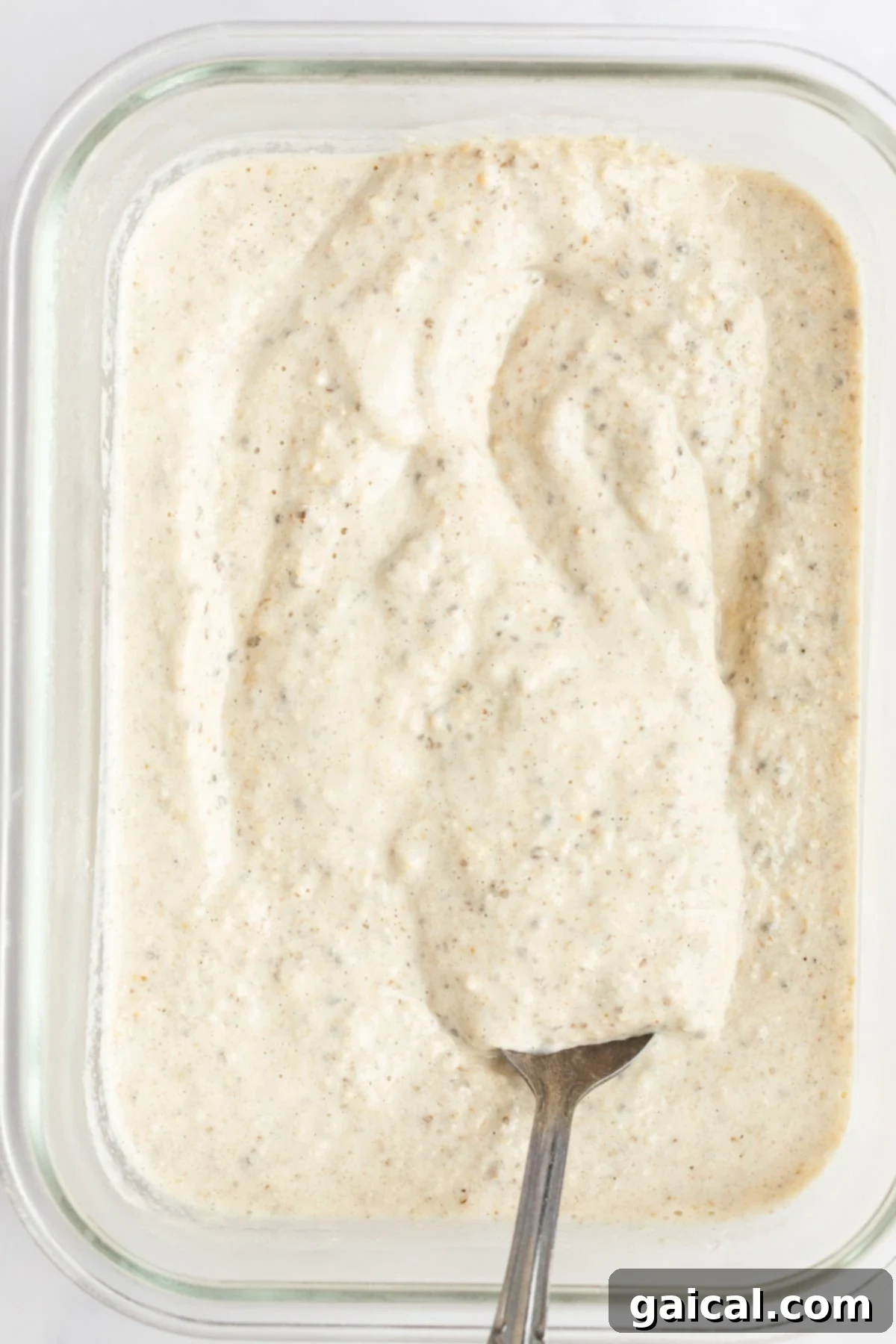 A close-up shot of creamy Peanut Butter Overnight Oats in a glass jar, generously topped with extra peanut butter and miniature chocolate chips.