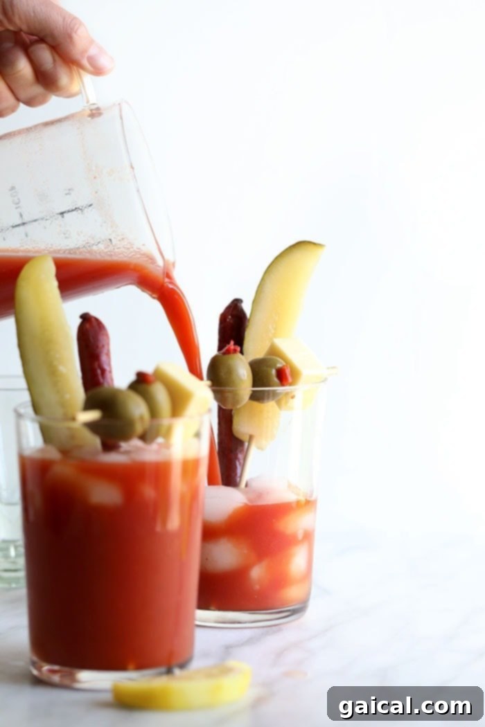 Pouring Bloody Mary mix into a glass with ice