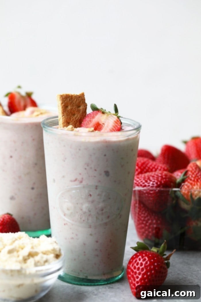 What's better than cheesecake for breakfast? NOTHING! You're going to love this Strawberry Protein Smoothie because it tastes exactly like strawberry cheesecake. This protein powder smoothie recipe is made with just a few simple ingredients: frozen strawberries, bananas, vanilla protein powder, Greek yogurt, and almond milk. Two glasses of strawberry cheesecake protein smoothie, garnished with graham cracker crumbs, ready to be enjoyed.