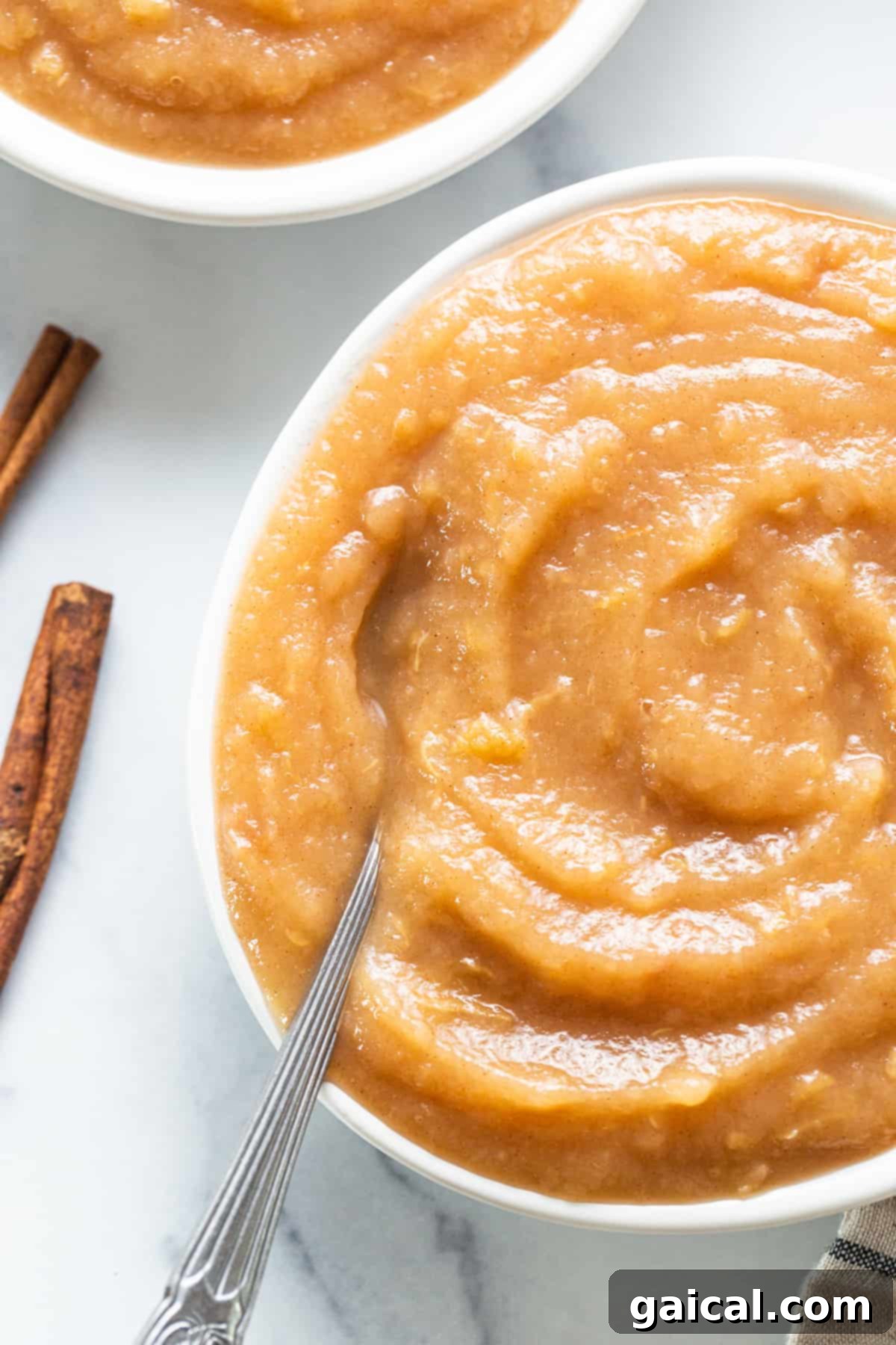Easy Homemade Instant Pot Applesauce 6 A bowl of applesauce next to a pile of fresh apples, emphasizing the farm-to-table freshness of homemade applesauce.