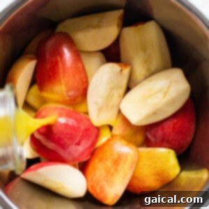 Sliced apples in a bowl with a liquid pouring over them.