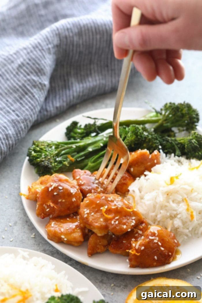 Cooked orange chicken glistening with sauce in a hot frying pan, ready to be served.
