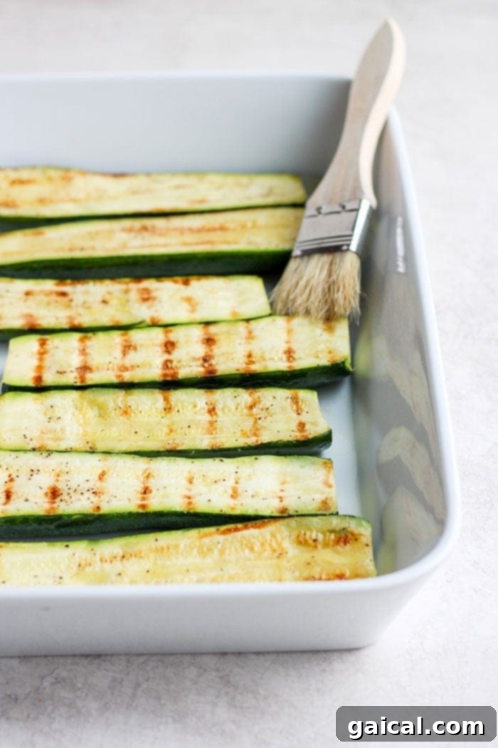 Turn on the grill and throw on some zucchini! Making grilled zucchini is easy and if you do it right you'll end up with grilled zucchini with a little crunch rather than a soggy mess. Grab the zucchini from your garden or the grocery store and get grilling! Grilled zucchini slices arranged in a white baking dish, ready to serve.