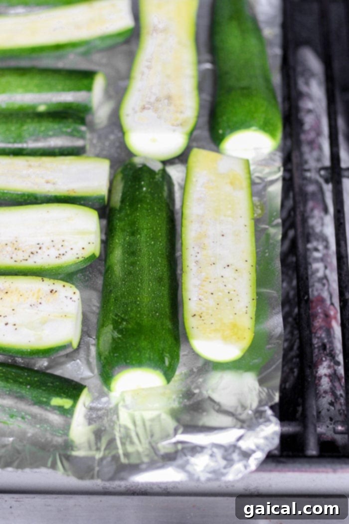 Turn on the grill and throw on some zucchini! Making grilled zucchini is easy and if you do it right you'll end up with grilled zucchini with a little crunch rather than a soggy mess. Grab the zucchini from your garden or the grocery store and get grilling! Zucchini halves grilling on foil on a barbecue, showing light char marks.