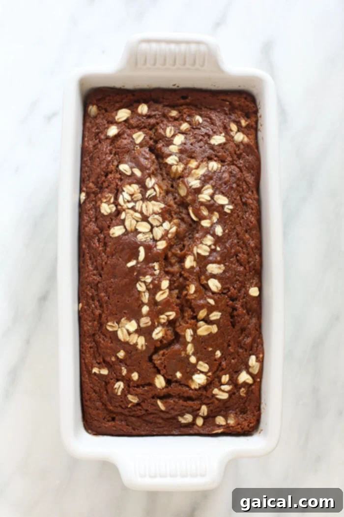A freshly baked Cinnamon Apple Bread loaf sitting in a dark loaf pan.