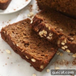 A slice of pumpkin bread with cinnamon and oats on a white plate.