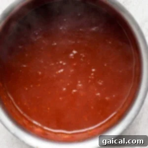 Homemade BBQ sauce simmering on low heat in a saucepan.