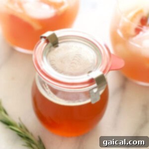 Golden Honey Elixir 2 A glass jar with orange juice, honey simple syrup, and a rosemary sprig.