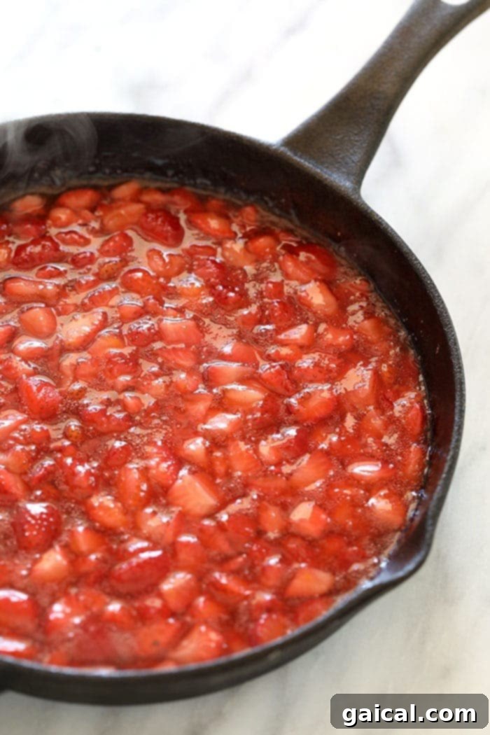 These Strawberry Oatmeal Bars are your summer dessert dreams come true! With an easy to make crust and crumble topping, and a filling made of sliced fresh strawberries reduced to perfection (with no added sugar!), these oatmeal bars are the best strawberry dessert to enjoy all summer long! Enjoy! A rich, red strawberry filling, perfectly reduced and thickened, in a cast iron skillet, ready to be layered into the oat bars.