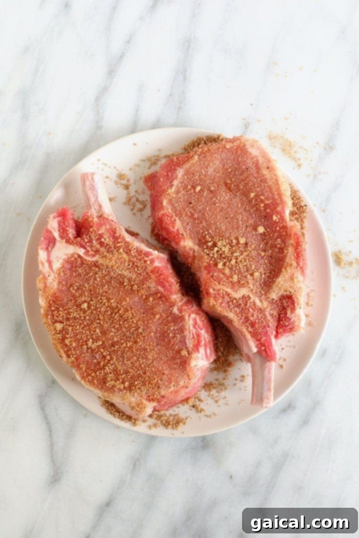 Pork chops fully coated in spice rub, ready for searing
