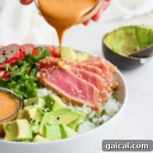 A person drizzling a creamy tahini sauce on a nutritious ahi poke bowl.