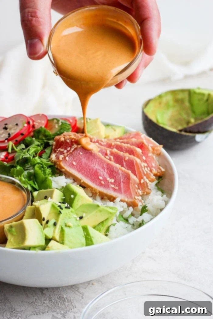 Drizzling almond dressing onto an assembled poke bowl
