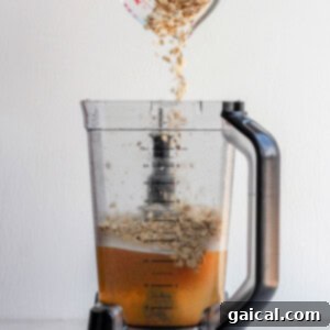 Craft Your Own Oat Milk 5 Adding dry old-fashioned oats into a blender filled with water and dates for homemade oat milk preparation.