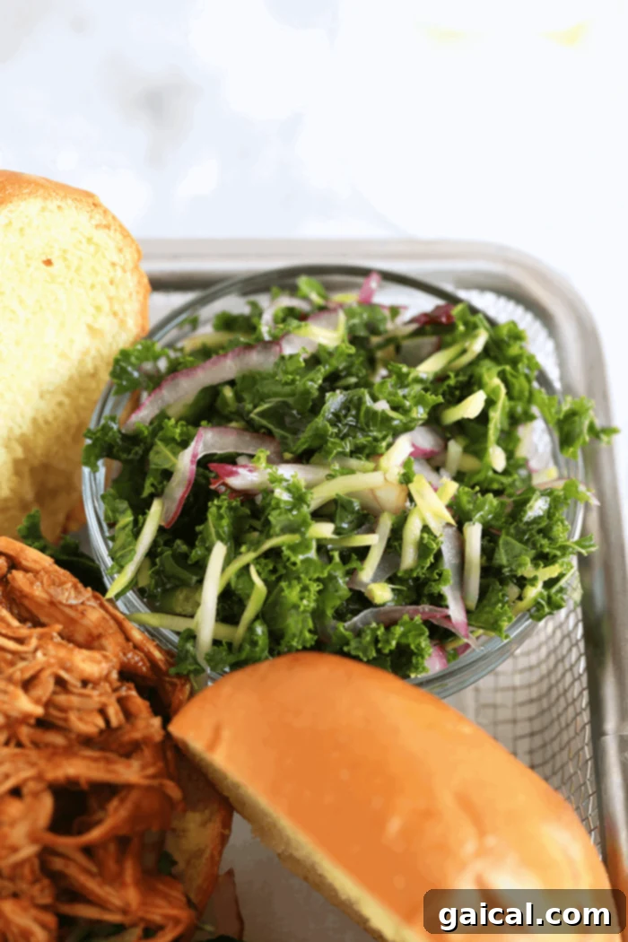 Homemade Kale Slaw: A vibrant side for your Slow Cooker BBQ Pulled Chicken. A vibrant homemade kale slaw, featuring thinly sliced red onions and a zesty dressing, perfect as a side dish.