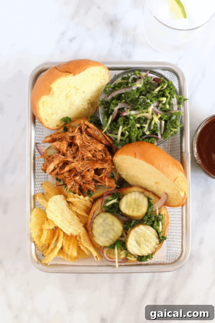 The best pulled BBQ chicken crockpot recipe, made with an epic dry rub and your favorite BBQ sauce. Double or triple for gatherings! A beautifully presented basket containing slow cooker BBQ pulled chicken sandwiches, crispy chips, and fresh slaw.