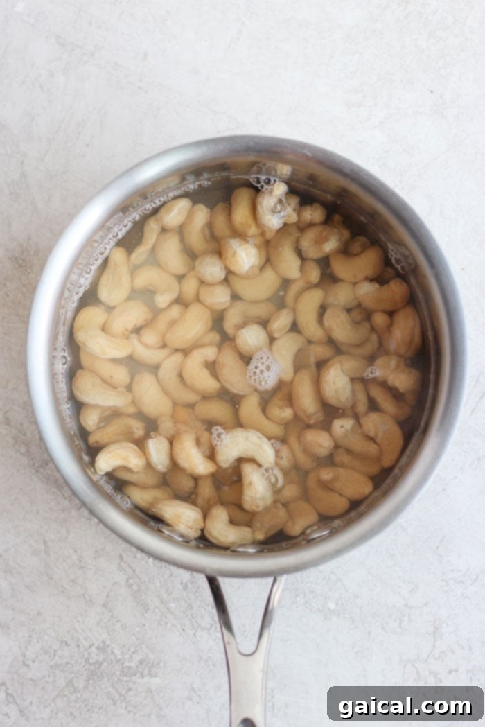 Raw cashews soaking in a saucepan after being flash-boiled, ready to be blended into a creamy sauce.