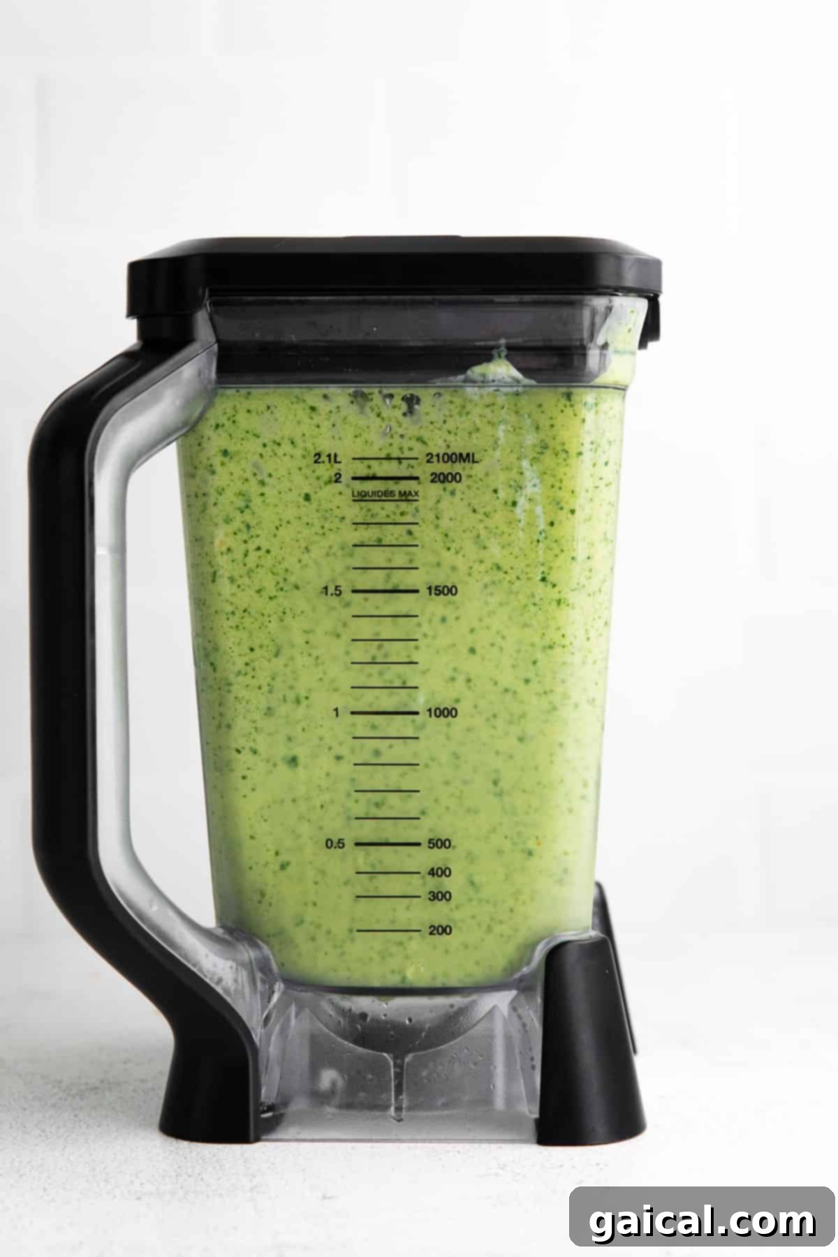 Island Green Power Smoothie 5 A vibrant green tropical spinach smoothie expertly blended and poured into a glass, showcasing its smooth, creamy texture.