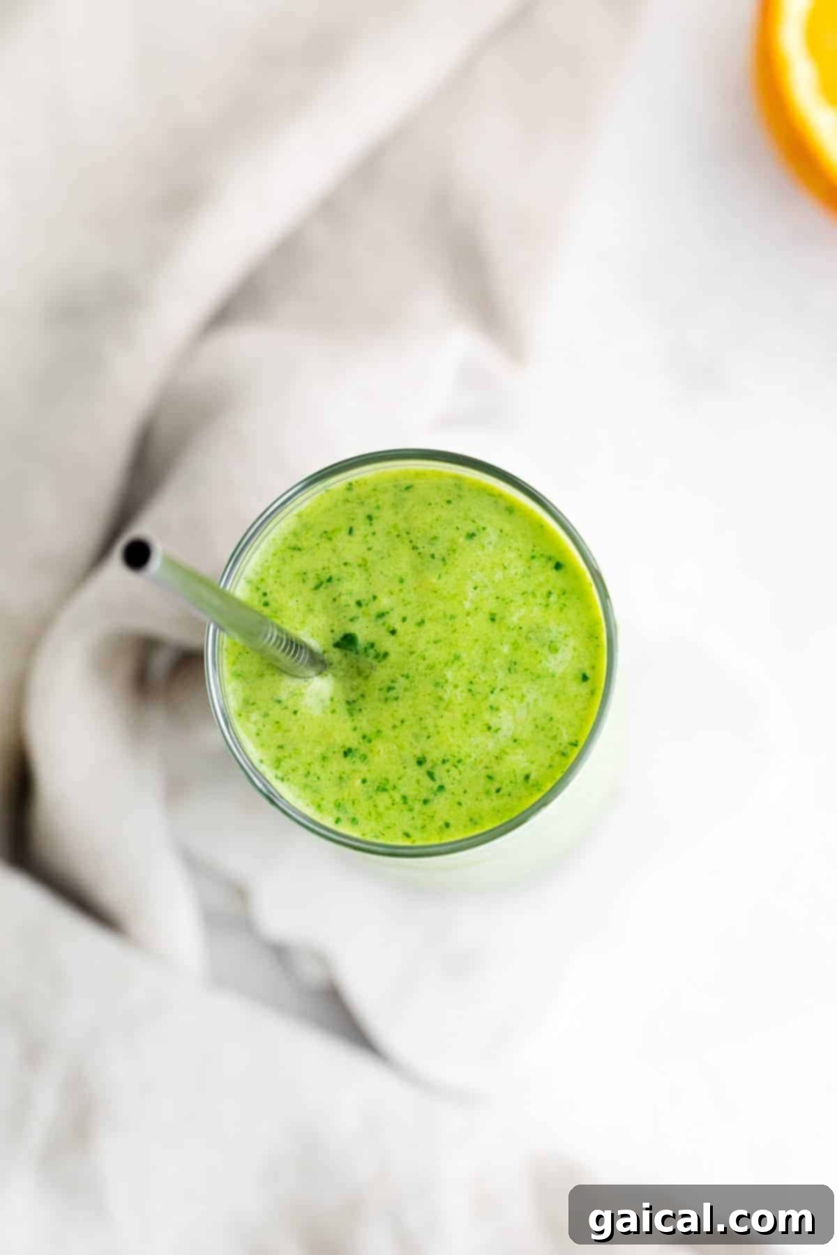 Island Green Power Smoothie 6 A close-up top-down view of a vibrant green tropical spinach smoothie in a clear glass, highlighting its smooth, inviting texture and color, garnished subtly.