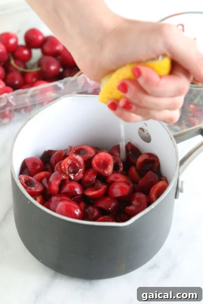 The secret to a perfect cherry filling is gentle simmering. Squeezing fresh lemon juice into a saucepan filled with vibrant red cherries, ready for simmering.