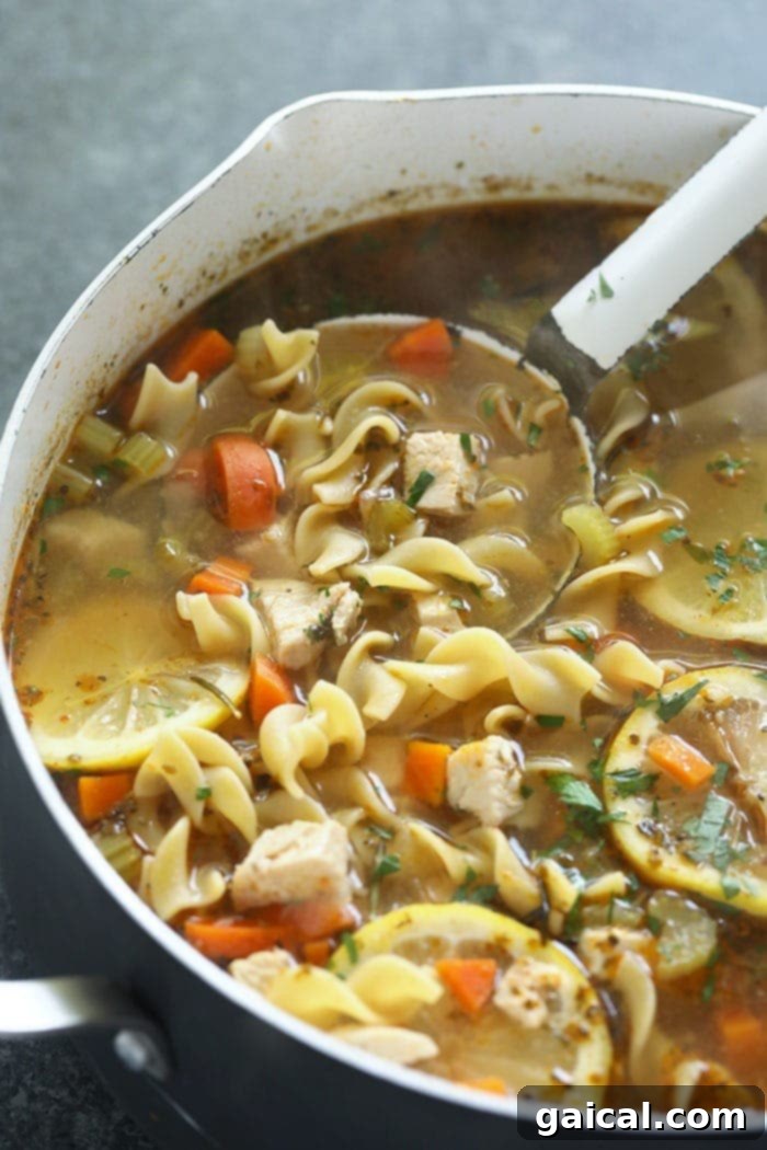 A large stockpot filled with homemade chicken noodle soup simmering on the stove.
