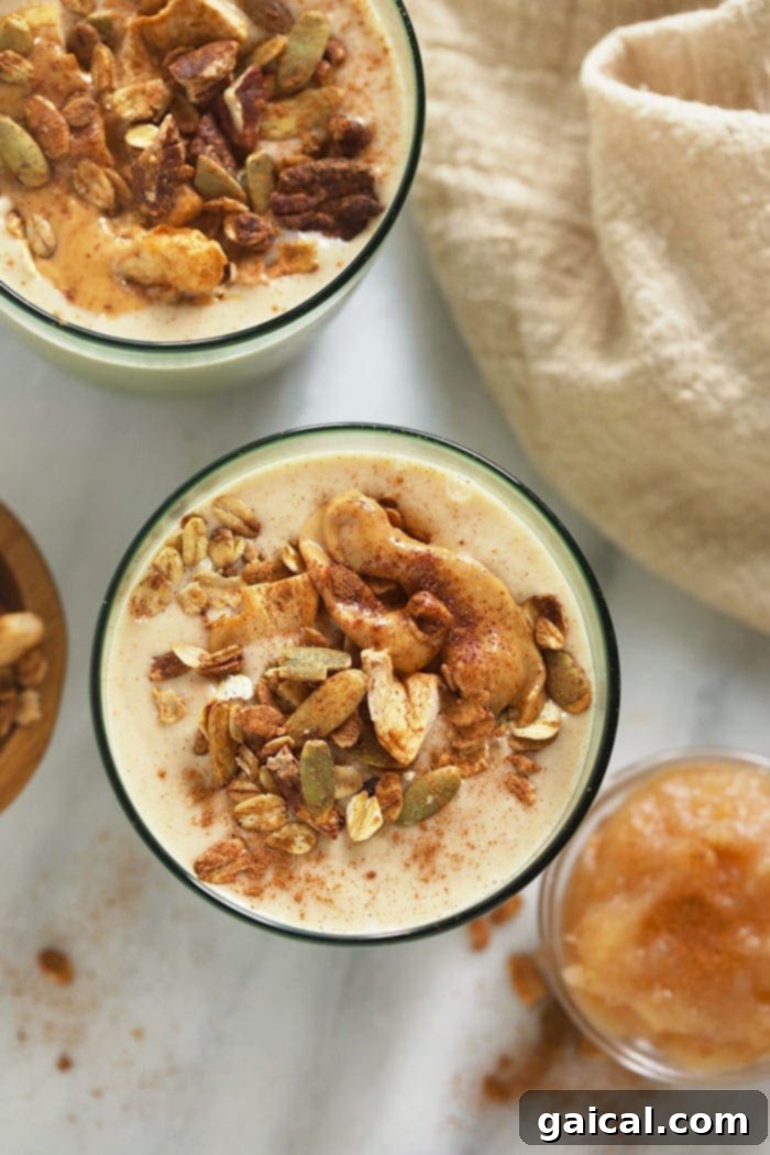 Crisp Apple Blend 4 A perfectly prepared apple smoothie, generously topped with a dollop of creamy nut butter and a sprinkle of crunchy granola, showcasing its inviting texture.
