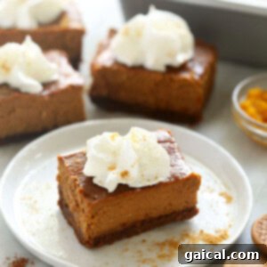 A finished pumpkin cheesecake bar garnished with whipped cream on a plate.