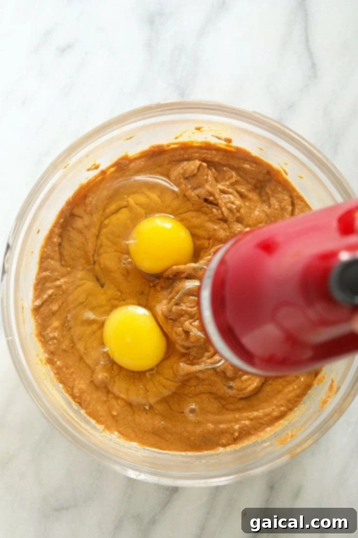 The creamy pumpkin cheesecake filling being meticulously mixed in a bowl, showing its smooth and rich texture before baking.