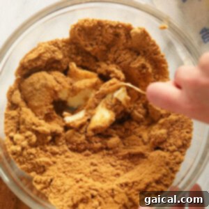 A person mixing gingersnap cookie crumbs, butter, and coconut oil for the crust.