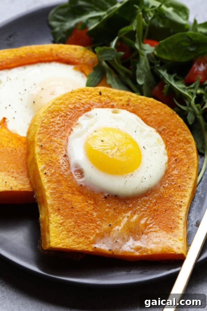 Two butternut squash eggs in a frame on a white plate, garnished with black pepper, a healthy and easy breakfast.