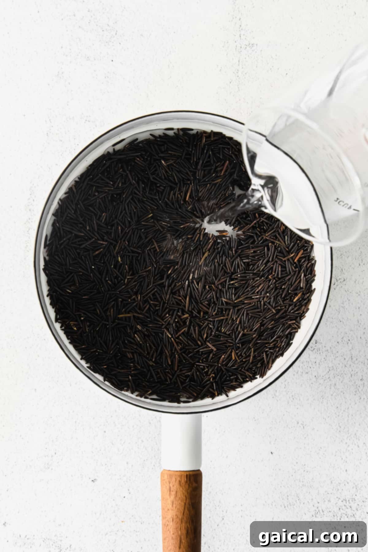 Wild rice is a great addition to so many meals! Check out how to make wild rice on the stove and in the Instant Pot. Both ways are easy and will have you using wild rice on a regular basis. Pouring water into a stockpot filled with dry wild rice kernels, ready for stove-top cooking.