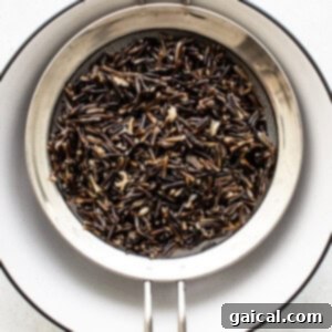 A strainer draining excess water from cooked wild rice.