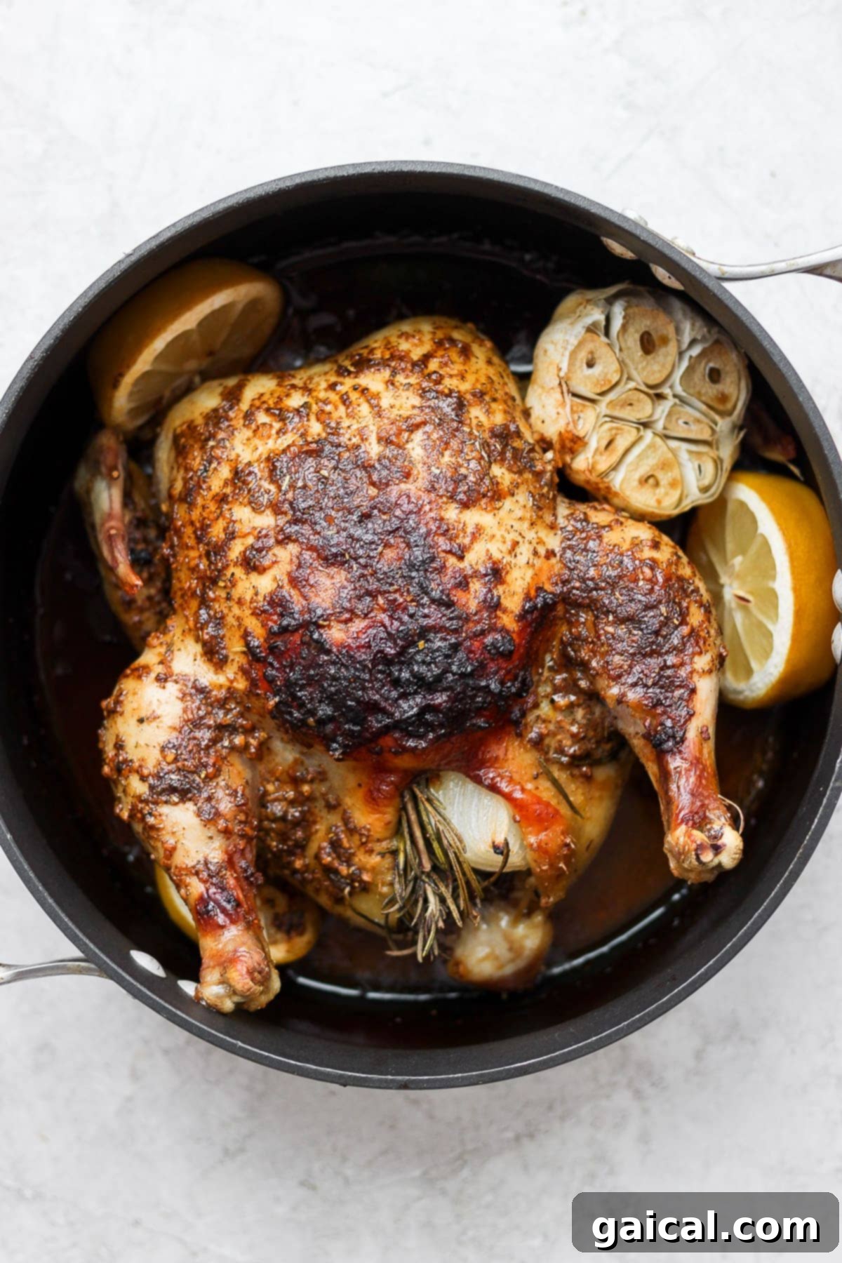 A close-up of a beautifully roasted whole chicken, carved into pieces and ready to be served, sitting in a pan.