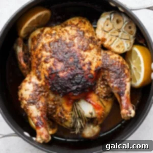 A perfectly roasted whole chicken, golden brown, with herbs and lemons, ready to be carved.