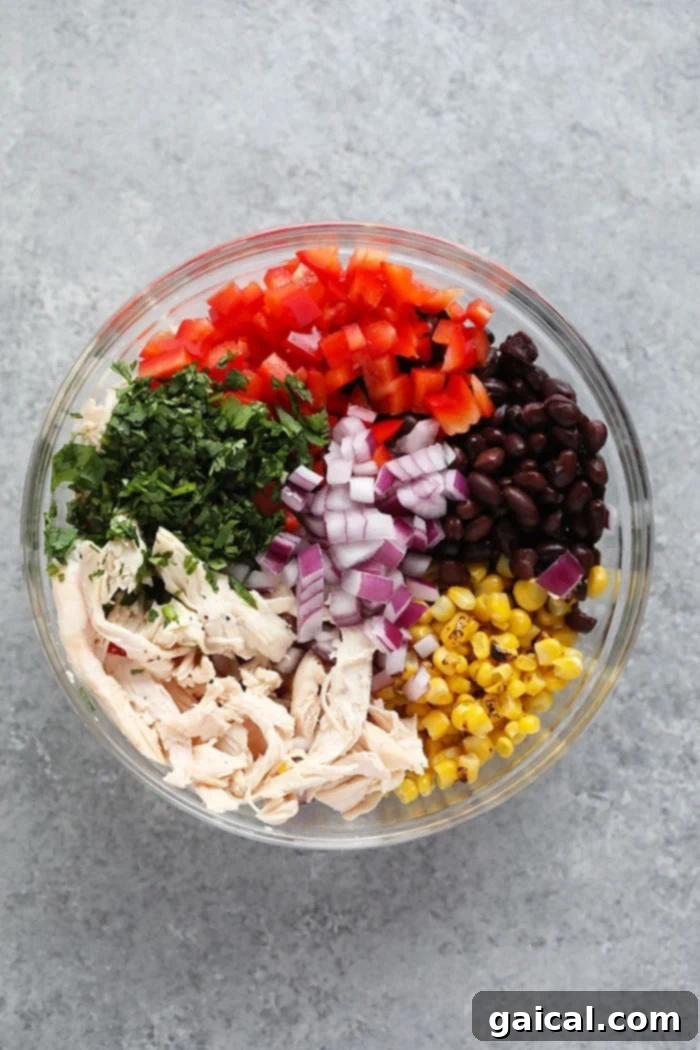 Fresh corn, black beans, red bell pepper, and cilantro await the zesty dressing. A large glass bowl showcasing the colorful, fresh ingredients of Southwest Chicken Salad, perfectly prepped before the dressing is added.