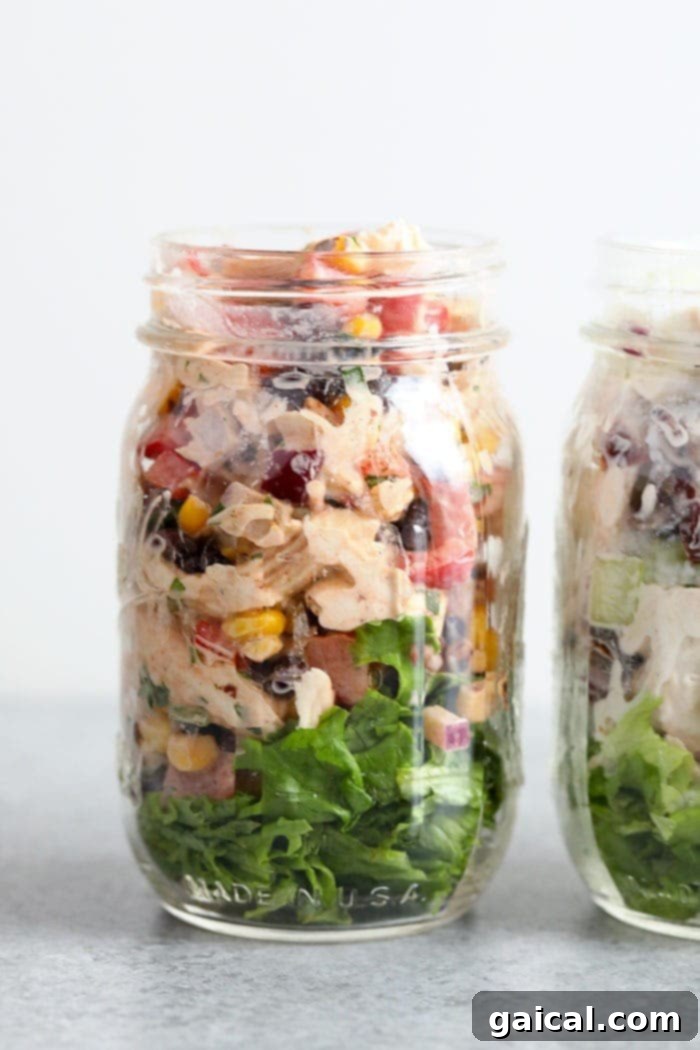 Convenient and healthy Southwest Chicken Salad packed in a jar for easy transport and fresh enjoyment. Southwest Chicken Salad beautifully layered in a mason jar with fresh lettuce at the bottom, showcasing a convenient and healthy meal on the go.