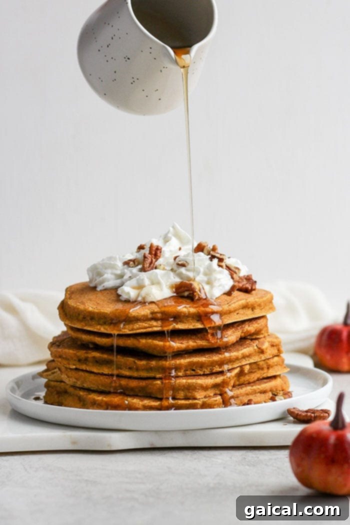 Dreamy Pumpkin Pancakes 5 A delicious stack of pumpkin pancakes being generously drizzled with maple syrup, capturing the essence of a perfect fall breakfast.