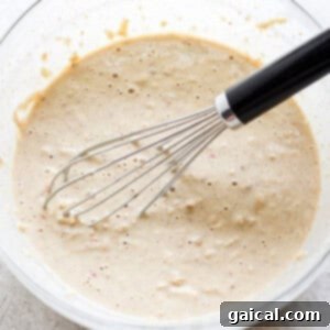 A bowl of pancake batter with a whisk, showing the combining of ingredients.