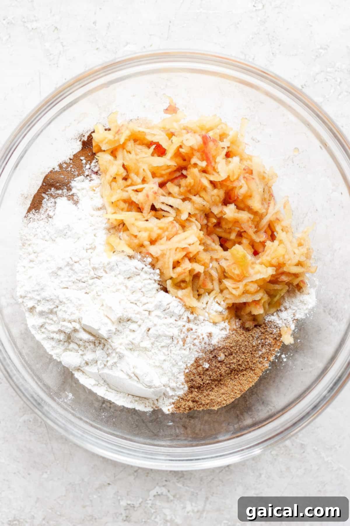 A bowl filled with a mixture of dry ingredients and grated carrots, showcasing fresh baking preparation.