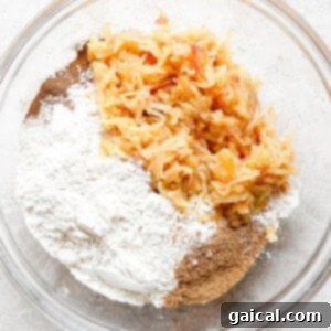 A bowl filled with flour, grated apples, and other dry ingredients for pancakes.