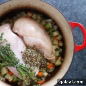 Silky Chicken Orzo Bliss 4 Raw chicken breast submerged in a flavorful broth with vegetables and fresh thyme sprigs, simmering in a large pot.