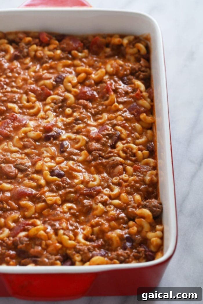 Perfectly baked Chili Mac and Cheese: a golden, cheesy masterpiece. Close-up of baked Chili Mac and Cheese in a casserole dish, showing the cheesy crust.