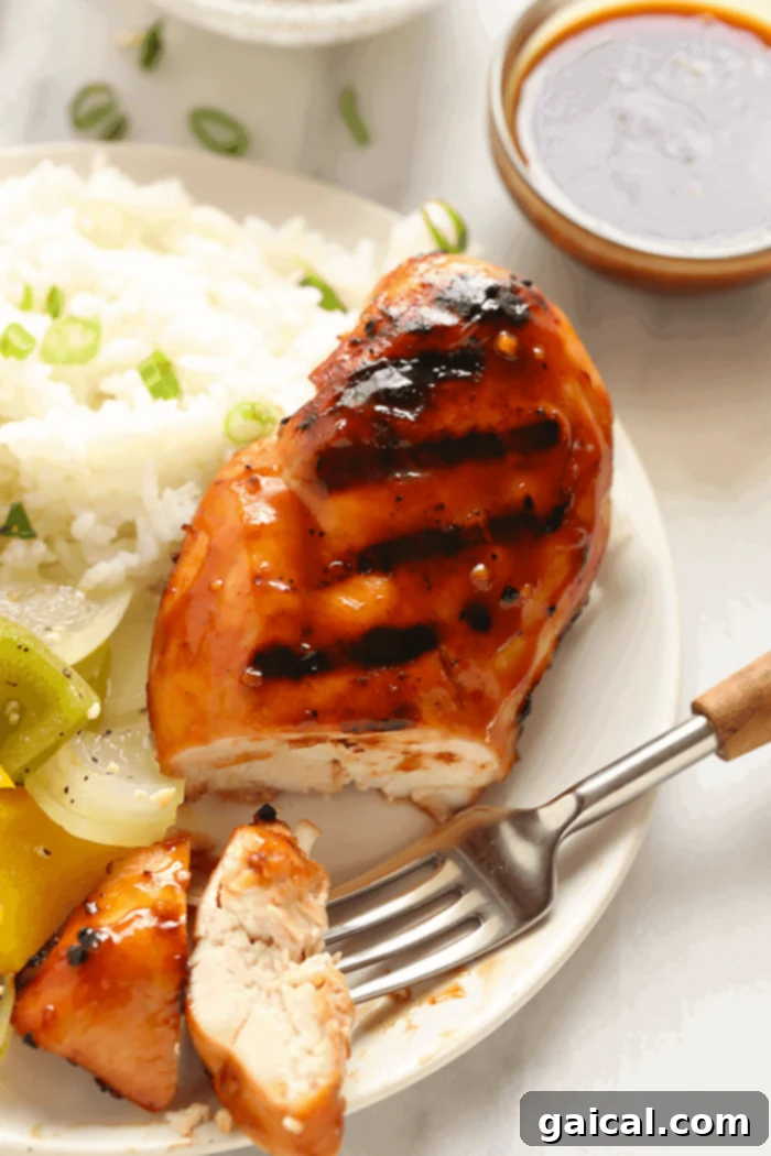 A sliced Teriyaki Chicken breast on a plate, garnished with fresh herbs and a drizzle of sauce.
