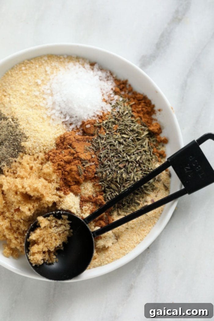 Key Spices for Homemade Pork Rub A close-up view of the seven essential ingredients for the pork rub, individually arranged on a surface, showcasing brown sugar, garlic powder, onion powder, coarse salt, cinnamon, dried thyme, and ground pepper.